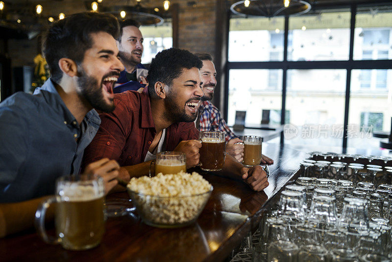 一群年轻快乐的朋友在酒吧里喝着啤酒玩乐