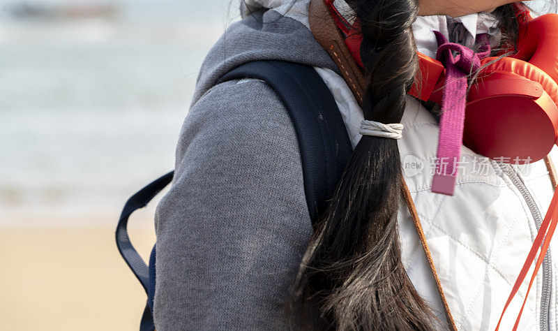 年轻女性戴着耳机躺在沙滩上