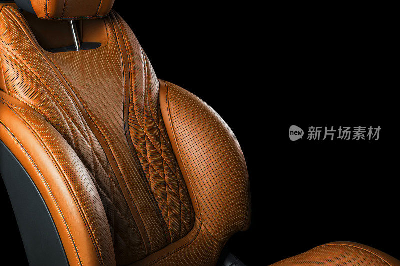 豪华现代汽车的棕色皮革内饰。穿孔橙色皮革舒适座椅与缝线隔离在黑色背景。现代汽车内部细节。汽车详细。汽车内部