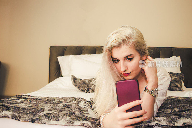 年轻女人在卧室里玩智能手机