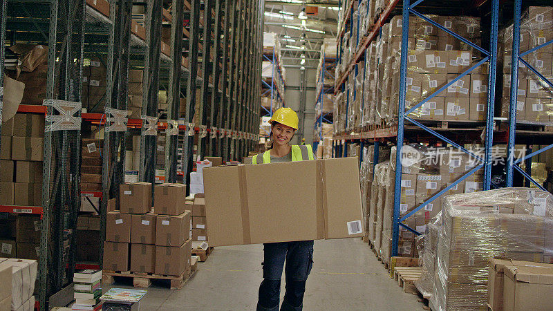 在仓库工作的女人。带着沉重的箱子