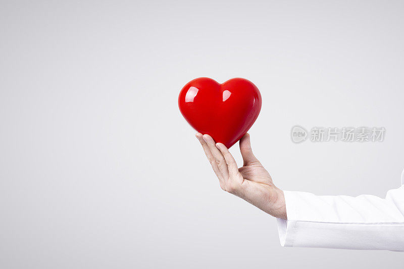 男医生怀里抱着心脏。医学中的保健和心脏病学概念