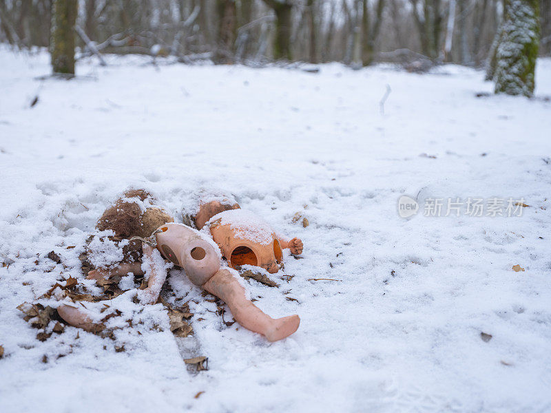 被遗弃的破损的旧娃娃在雪中腐烂