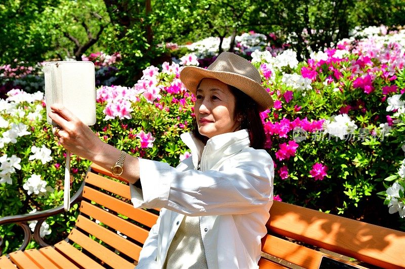 一名日本女子在公园里与盛开的杜鹃花自拍