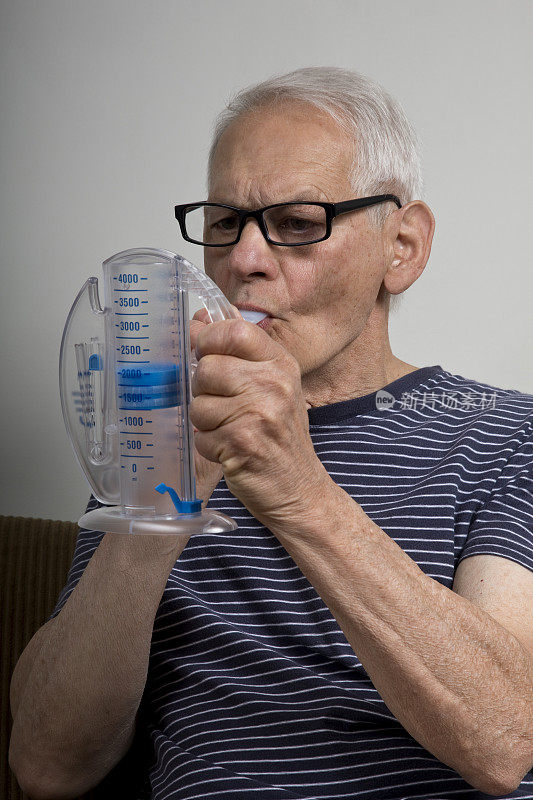 老男人在家里用肺量计吸气观察进展