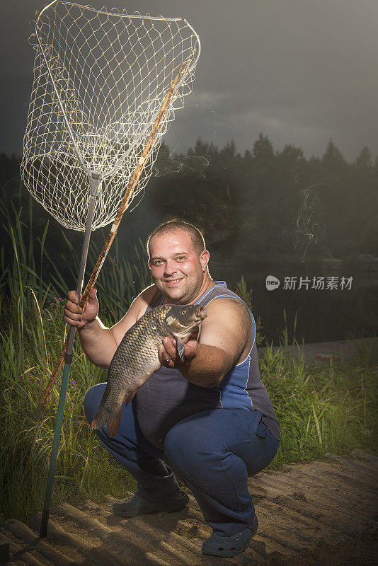 一个男人在湖上抓了一条鱼。