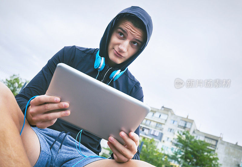 一个戴着耳机和平板电脑的十几岁男孩的肖像