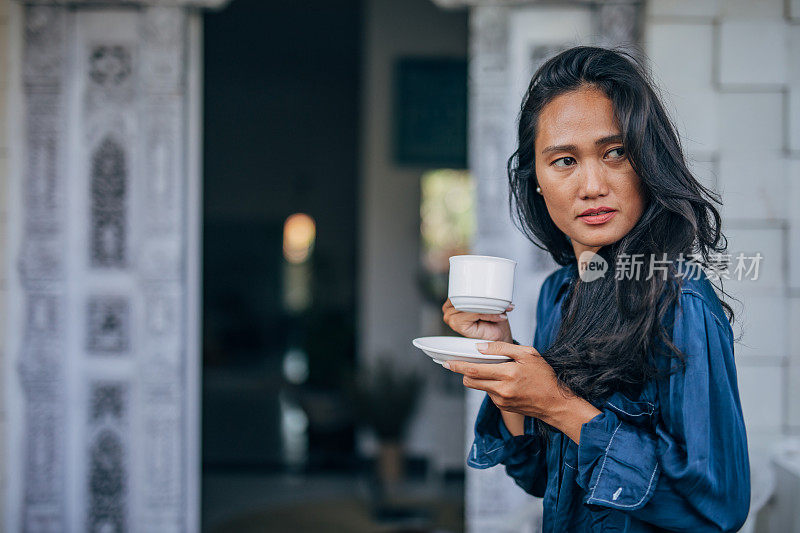 在阳台上喝咖啡的女士