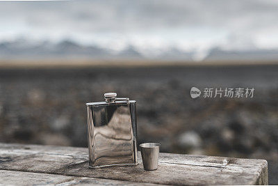 木桌上的金属烧瓶。背景是冰岛的风景