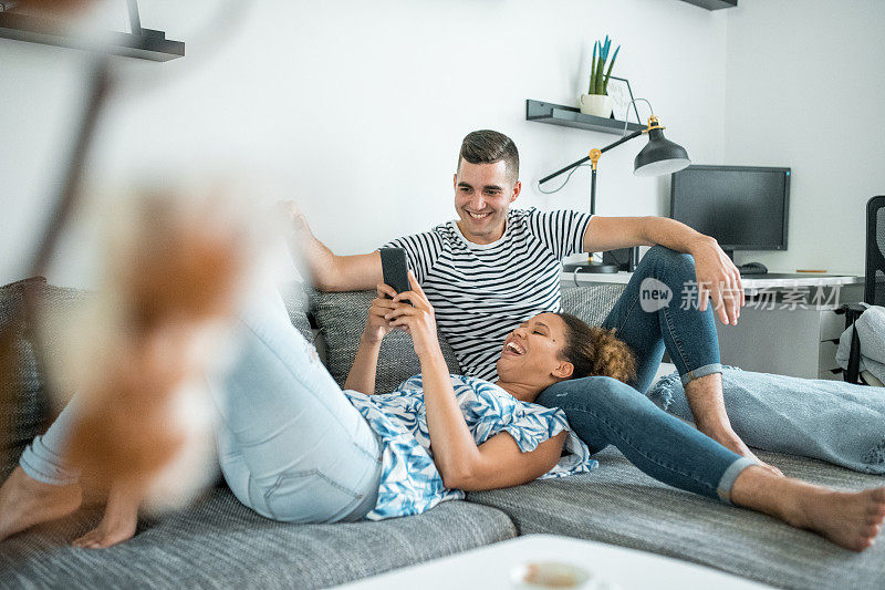 年轻女子躺在男友的腿上玩智能手机