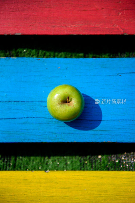绿苹果放在五颜六色的木板上