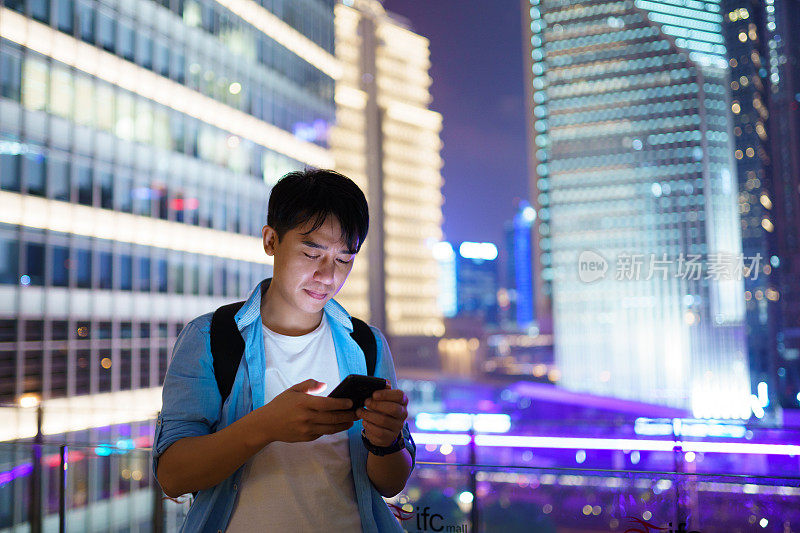 年轻的亚洲男子在晚上使用智能手机