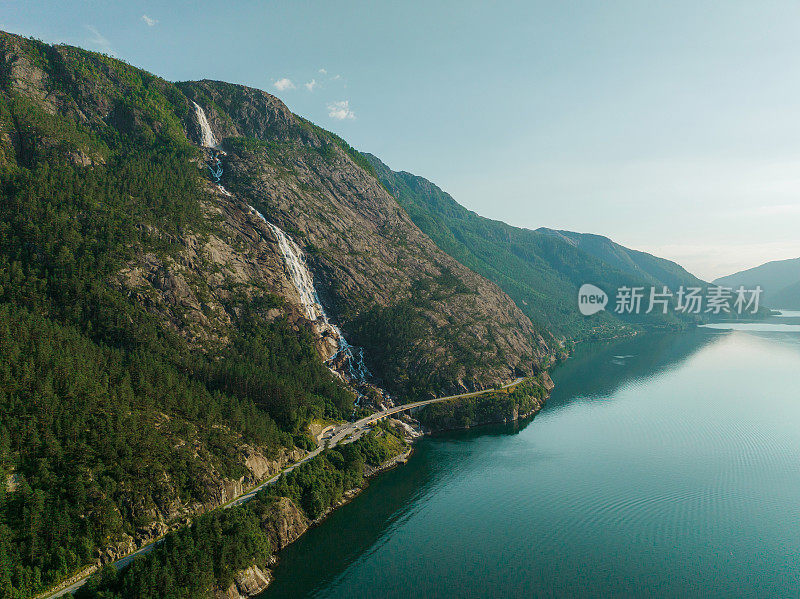 航拍的汽车在瀑布附近的道路上，落入挪威峡湾