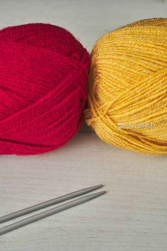 红色和橙色的羊毛球和编织针