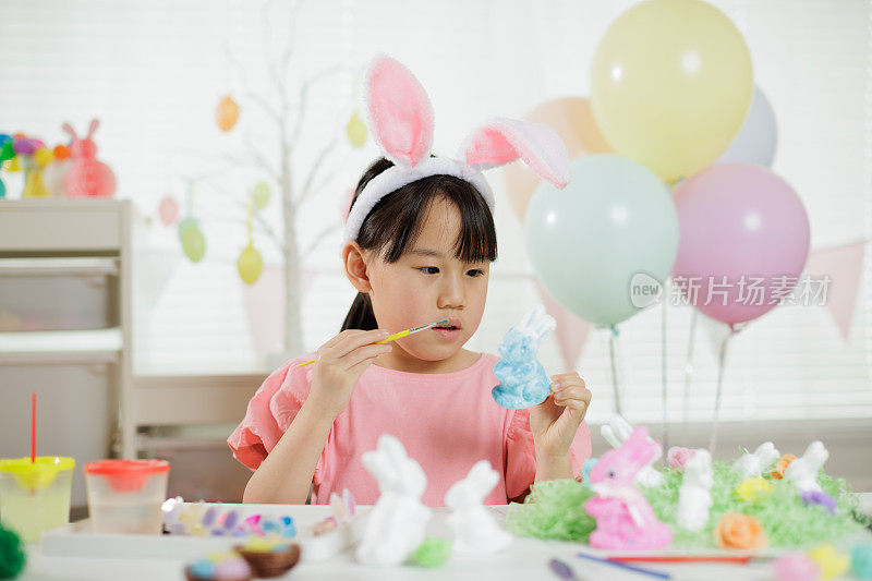 一个小女孩正在家里做复活节的工艺品和装饰品