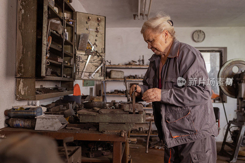 灵巧的老年妇女在车间使用工具