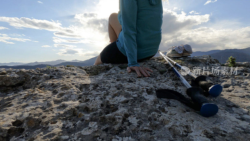 成熟的女徒步旅行者在远山的山顶上放松