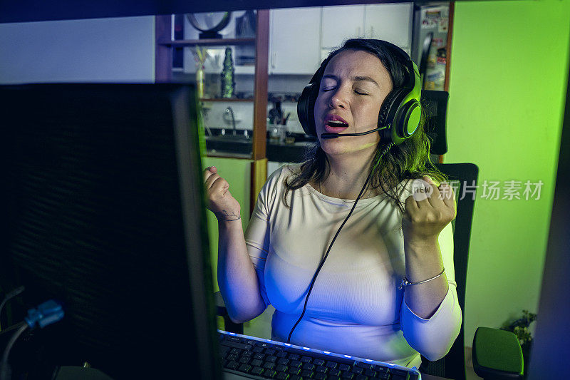 兴奋的拉丁玩家戴着耳机在家里玩在线视频游戏。