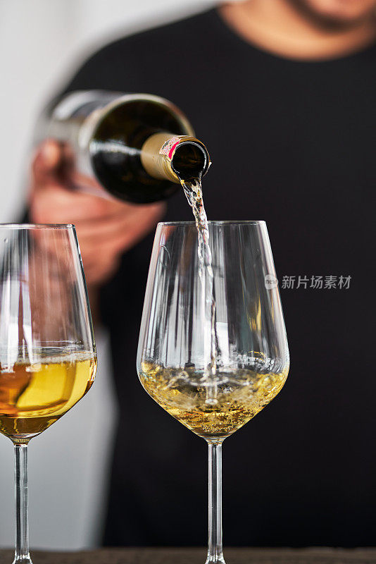 酒保把白葡萄酒倒进杯子里。