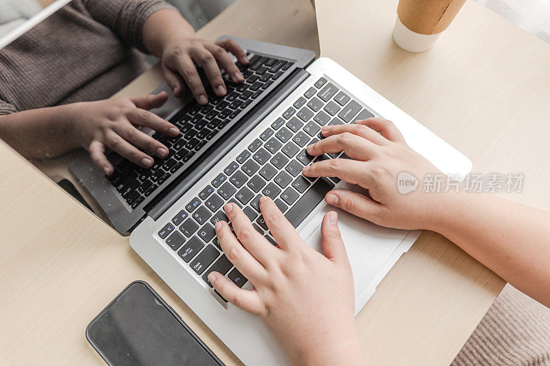 在家靠窗办公的女人拿着笔记本电脑和智能手机，喝着咖啡