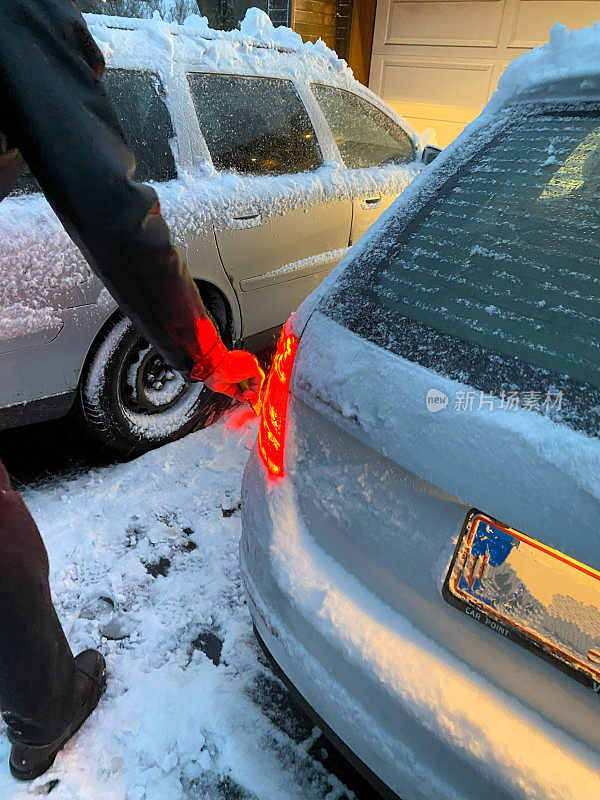 一名男子正在清除汽车上的积雪