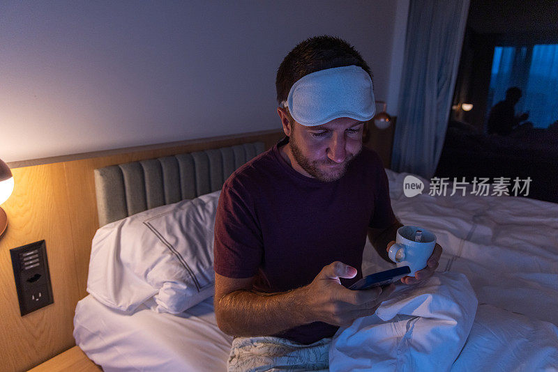 夜间难以入睡的男性在床上使用手机，睡眠障碍和失眠