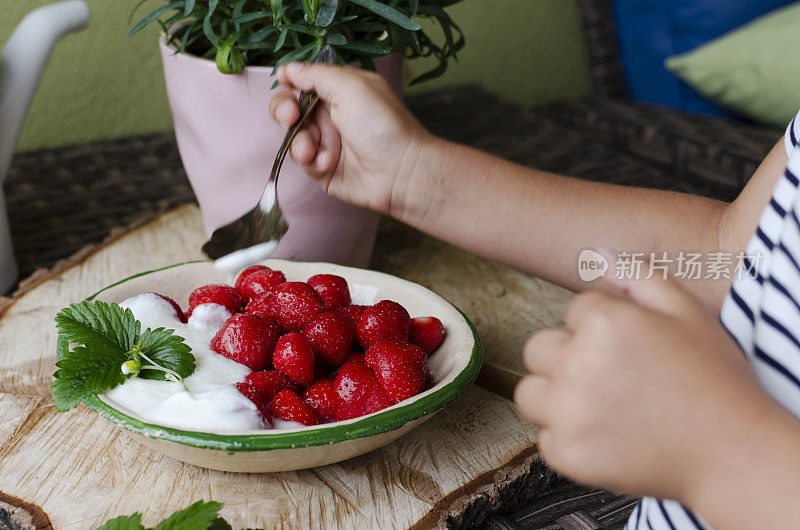 草莓放在孩子手里的勺子上，这样就可以吃了。含有维生素的健康食品。生水果在碗里。特写镜头。