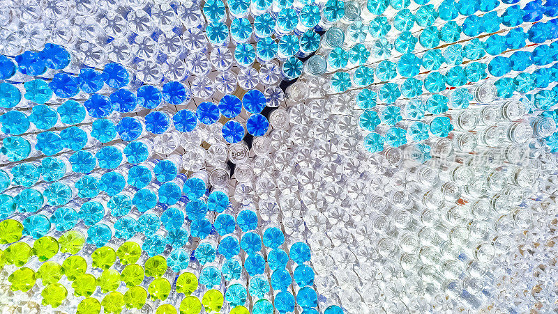 正下方的装饰天花板窗帘是由回收的塑料饮料瓶制成的，瓶子里装满了五颜六色的水，表面反射着美丽的光