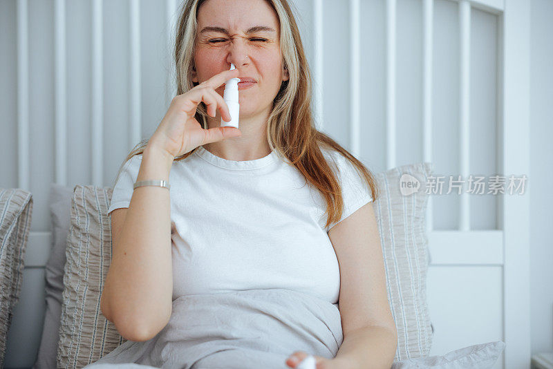 生病的年轻女子使用鼻腔喷雾剂