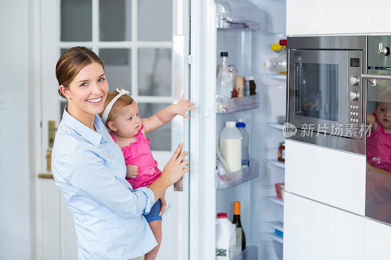 女人抱着小女孩打开冰箱