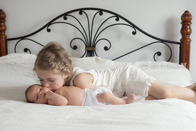 小妹妹在床上亲吻刚出生的弟弟