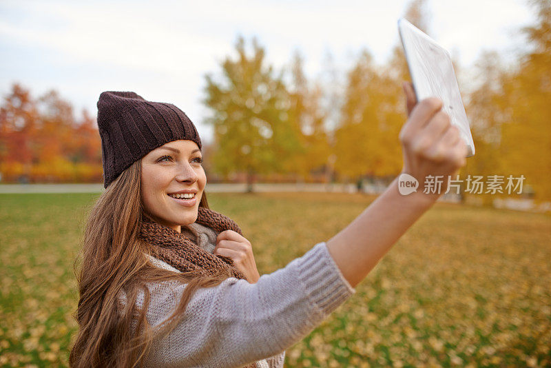 美丽的年轻女子和她的数字平板电脑在公园里