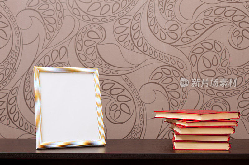 画框和书在书桌上与花卉墙纸背景