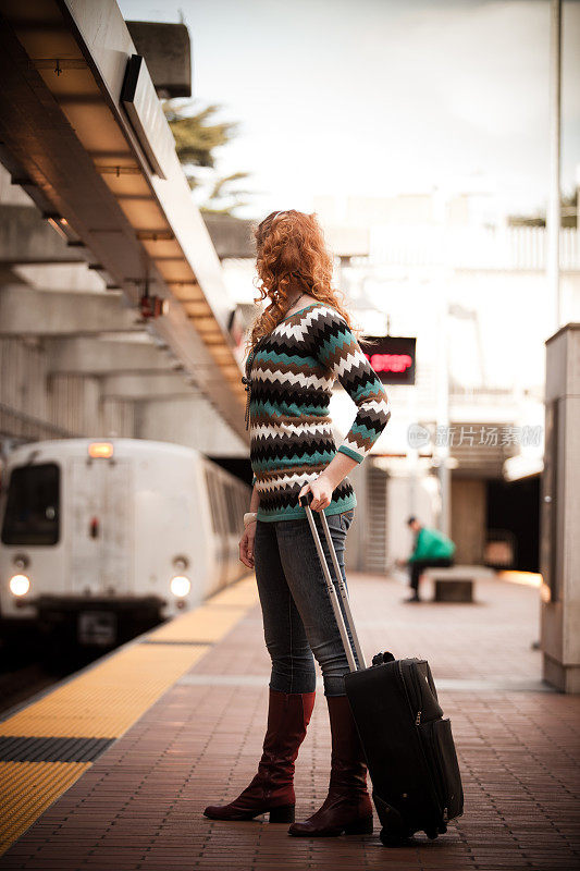 女孩拿着行李箱看着捷运列车到达