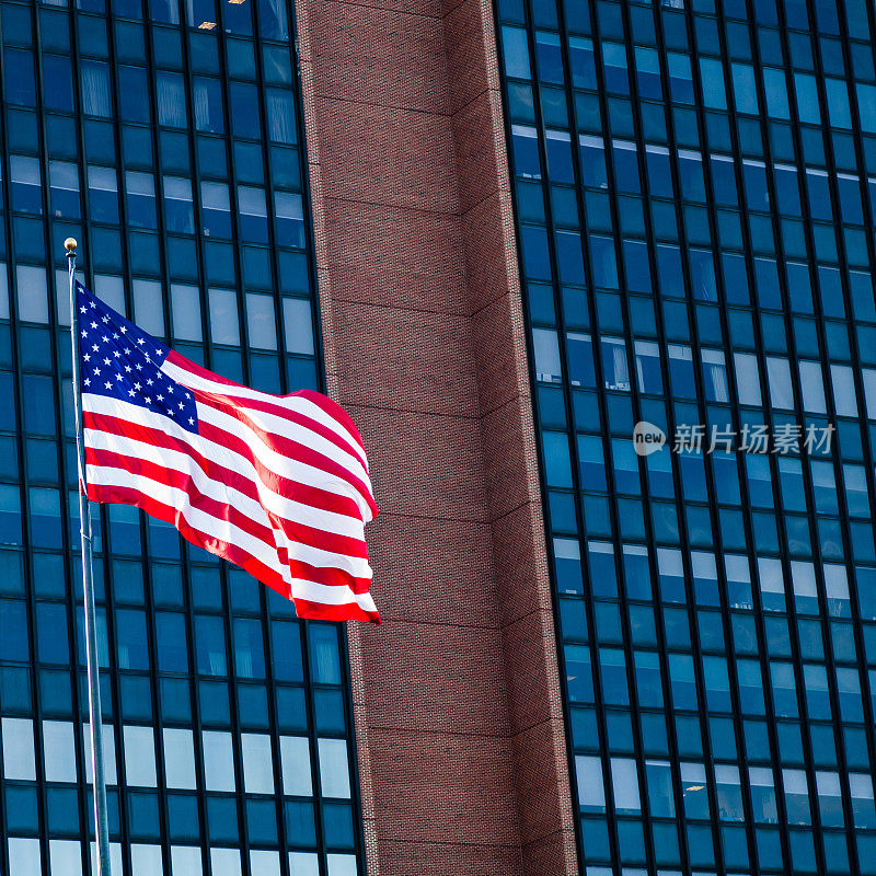 在玻璃幕墙的办公大楼前挥舞美国国旗