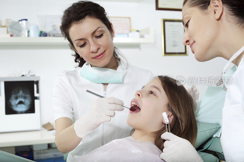 牙医正在检查一个女孩的牙齿。