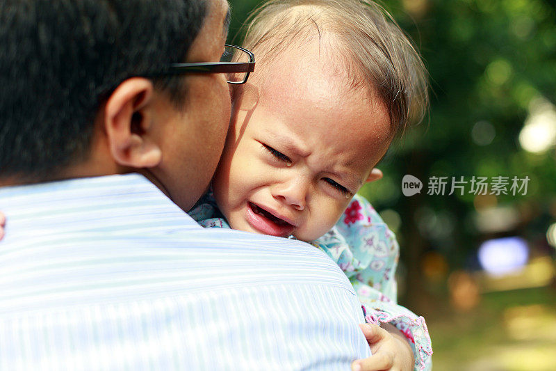 婴儿在她父亲的臂弯里哭泣