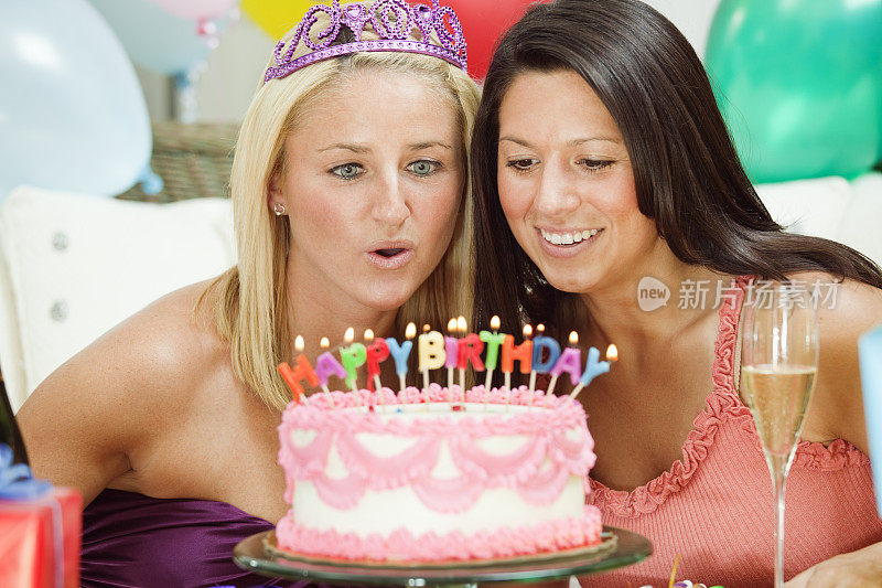 年轻的女性朋友吹灭生日蛋糕上的蜡烛
