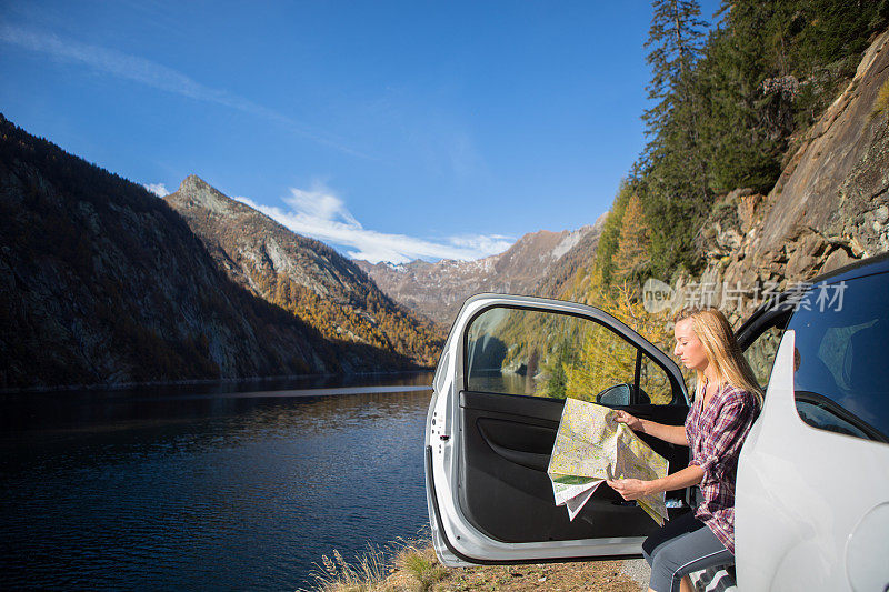 游客坐在湖边的车里看地图指路