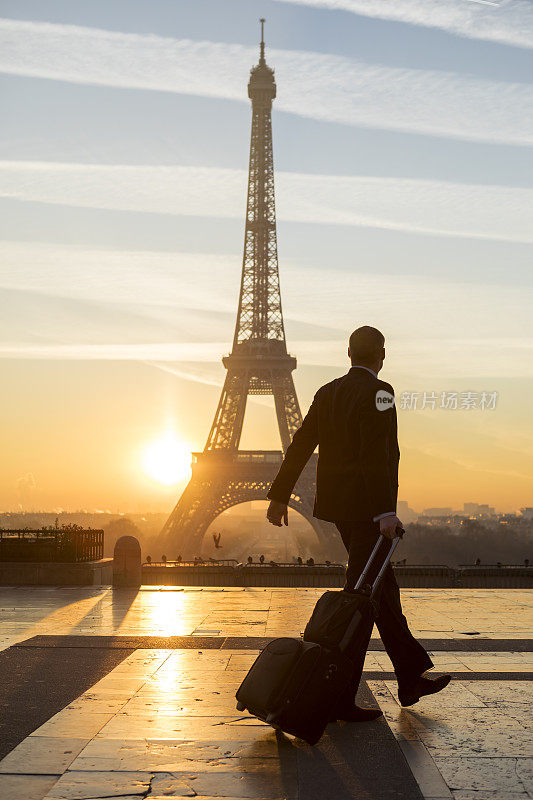 旅行家提着旅行箱走在巴黎埃菲尔铁塔上