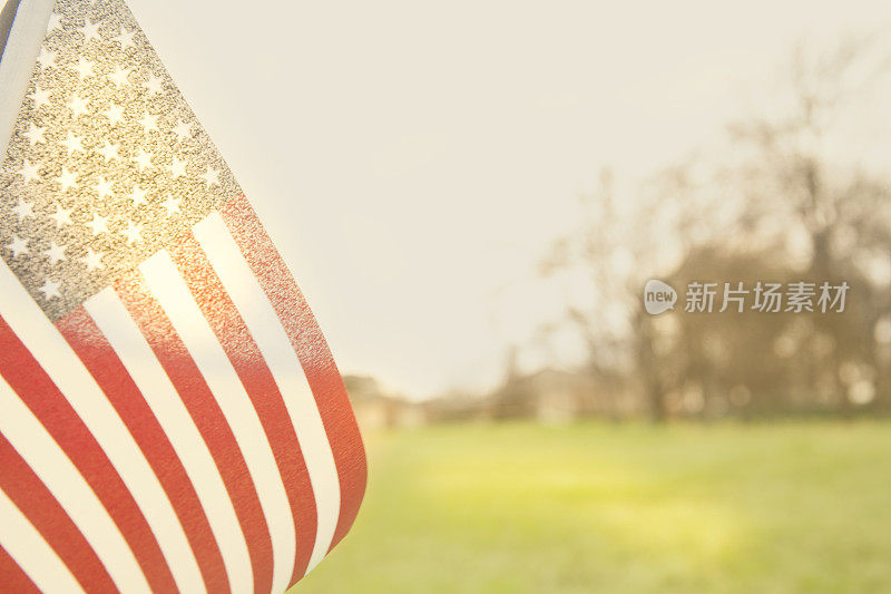 美国国旗在午后的阳光下飘扬在开阔的草地上。