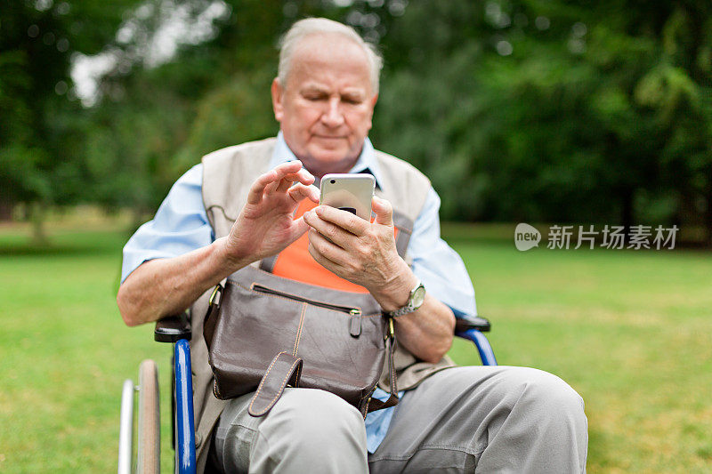 一位坐在轮椅上，使用智能手机的老人