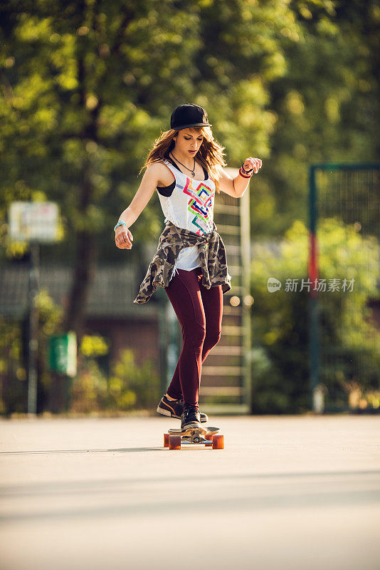 酷酷的年轻女子在公园滑长板。