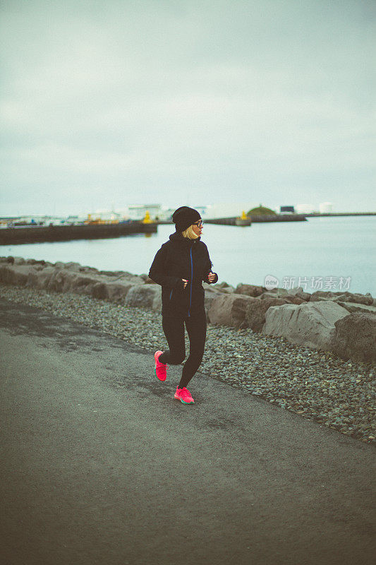 迷人和活跃的女人正在冰岛的道路上跑步