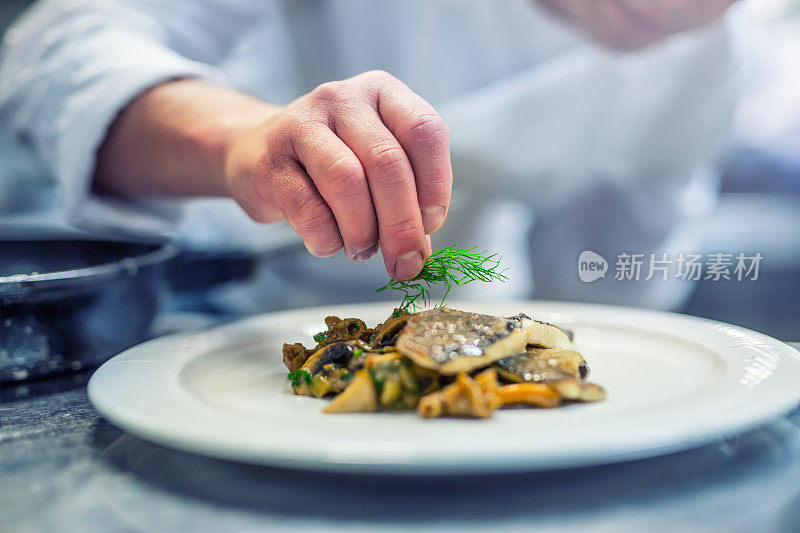 厨师在酒店或餐厅厨房做饭，只用手。配以莳萝装饰的鱼排