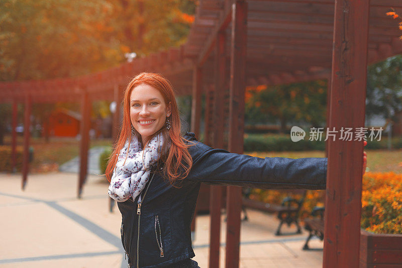 红发女人微笑着在公园里摆姿势