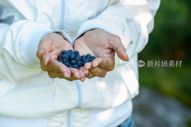 一个年轻女人手里拿着一把蓝莓