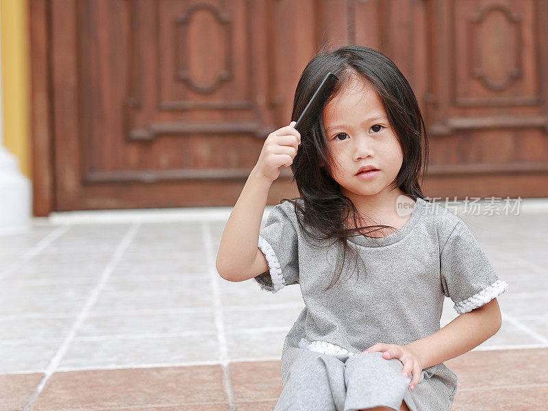 可爱的亚洲女孩梳理她的头发。
