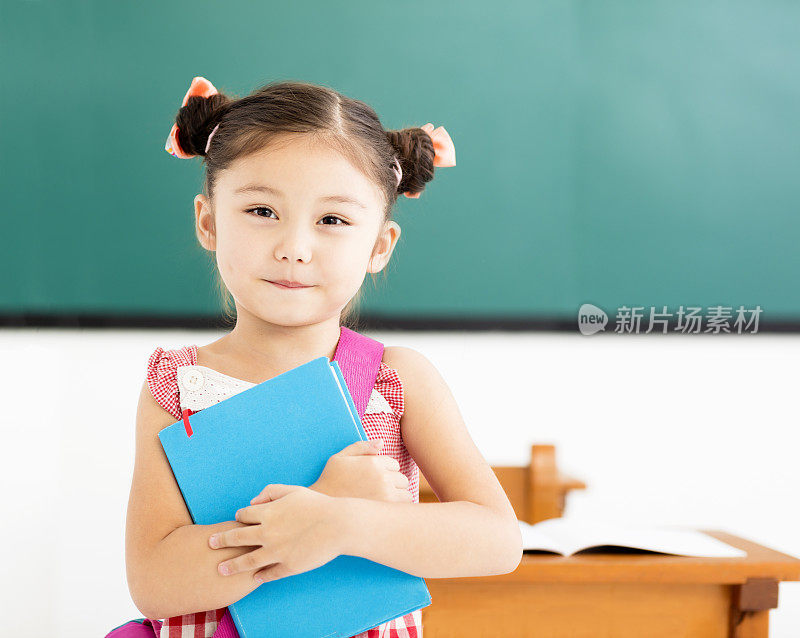 快乐的小女孩拿着书在教室里