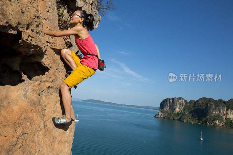 女攀岩者在海边悬崖上攀岩